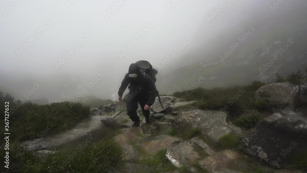 Man climbing a wet misty mountain in heavy rain Man climbing a wet misty mountain in heavy rain