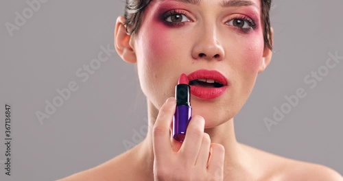 Woman makes makeup. Young woman paints her lips  with a lipstick. Cosmetic concept. Closeup face of a model with bright eye makeup. Beautiful girl with a fashion vivid make-up
