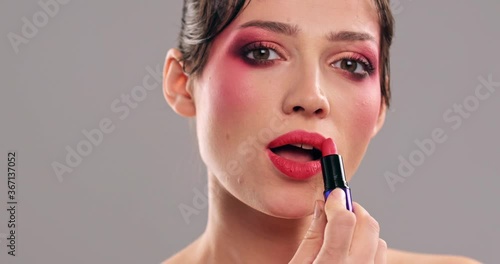 Woman makes makeup. Young woman paints her lips  with a lipstick. Cosmetic concept. Closeup face of a model with bright eye makeup. Beautiful girl with a fashion vivid make-up