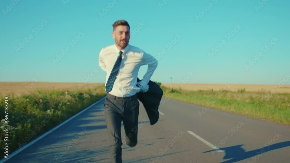 Shot of businessman runs removes the jacket country road near a wheat field freedom concept outdoors handsome winner jumping elegant slow motion Shot of businessman runs removes the jacket country road near a wheat field freedom concept outdoors handsome winner jumping elegant slow motion