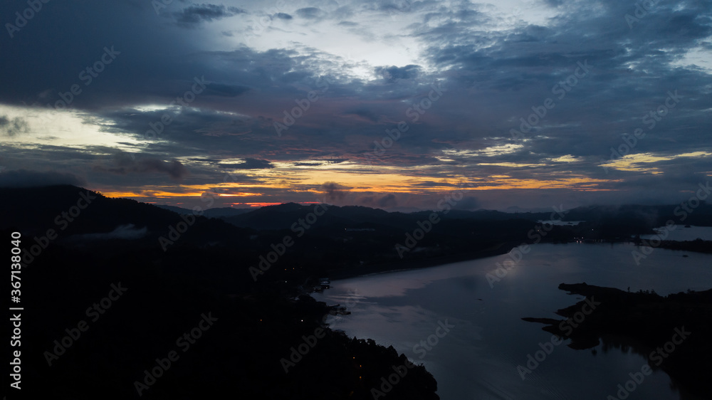 Aerial view of an amazing Colorful and Dramatic sunrise. Majestic Sunlight Cloud fluffy,Idyllic Nature Peaceful Background,Beauty Dark Blue Hour on Dusk,Purple Dawn Silhouette mountain on Kenyir Lake.