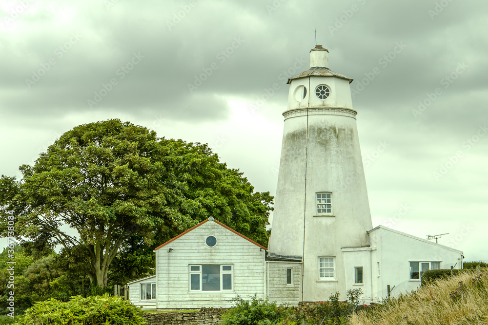 A dirty Sir Peter Scott Lighthouse stands proud against the dark clouds. A dirty Sir Peter Scott Lighthouse stands proud against the dark clouds.