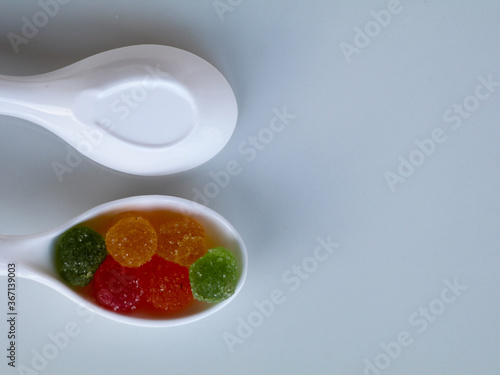 Sweet mixed color jelly candy in a white spoon against white background with copy space