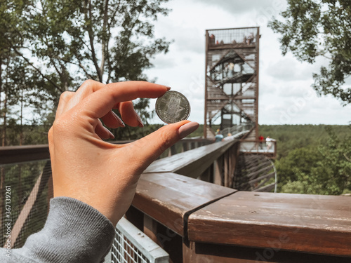 holding a coin in Laju The Treetop Walking Path observation tower photo