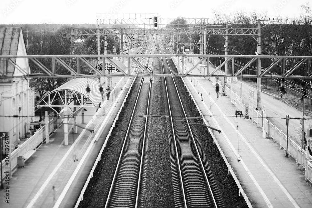 Black-and-white image of long railway tracks and half-empty stations. Waiting and sadness.