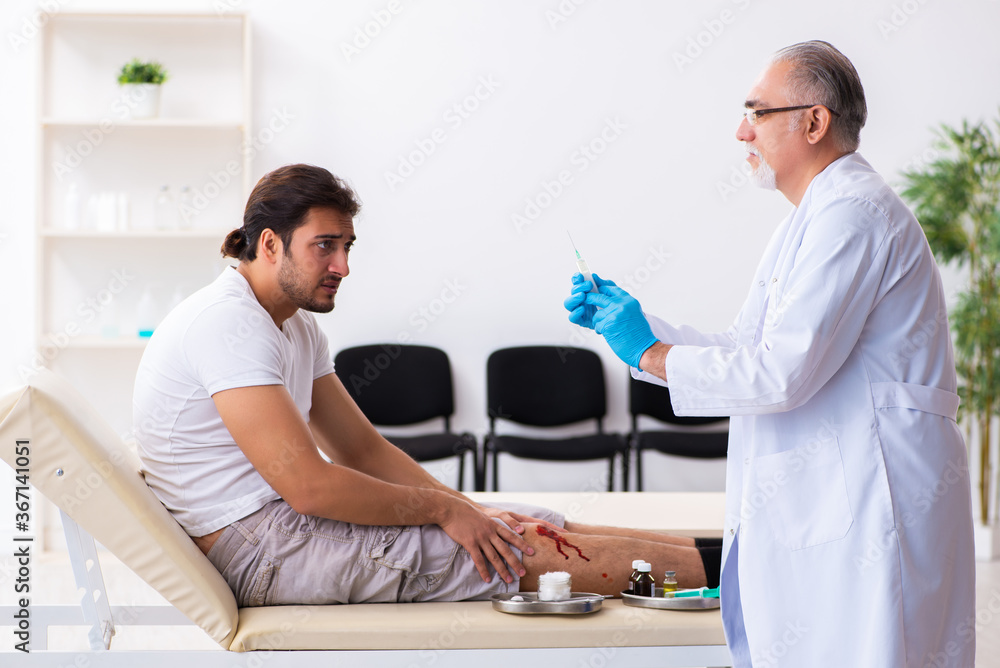 Leg injured man visiting old doctor in first aid concept Leg injured man visiting old doctor in first aid concept