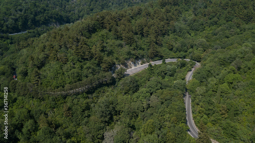 Aerial view from drone of curve road with a car on the mountain with green forest in Russia
