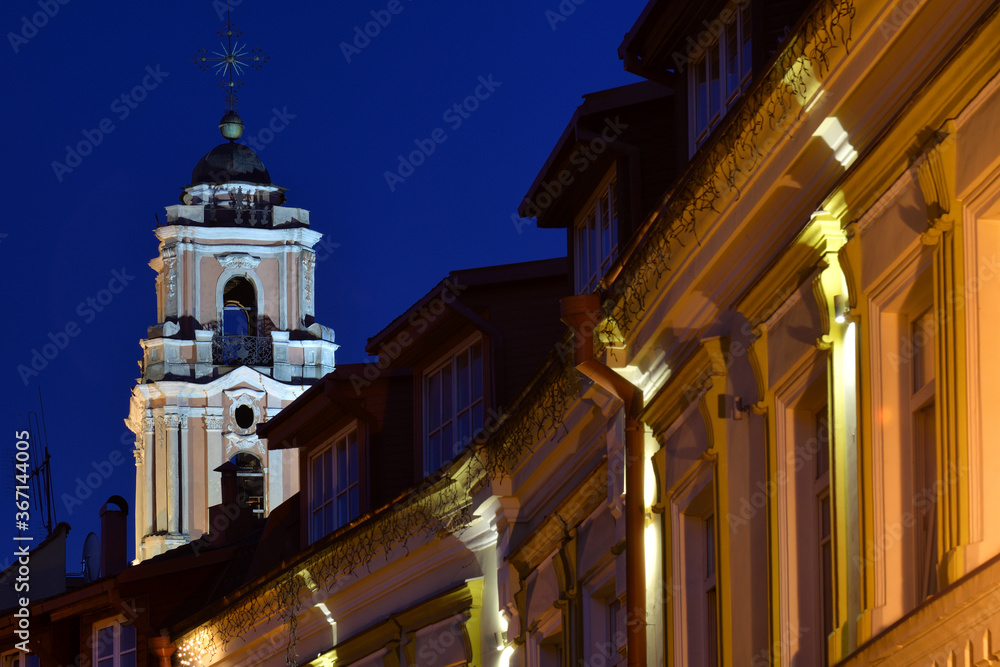 Cathedral tower over old houses at night in Vilnius, Lithuania