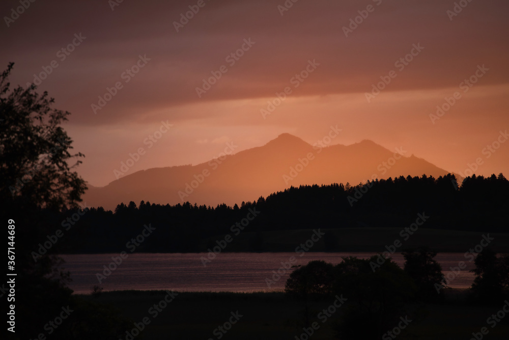Landschaftspanorama von den Bergen und einem See in der Luftperspektive bei Sonnnenuntergang. Südbayern, Schweiz  - Blauestunde/Goldenestunde