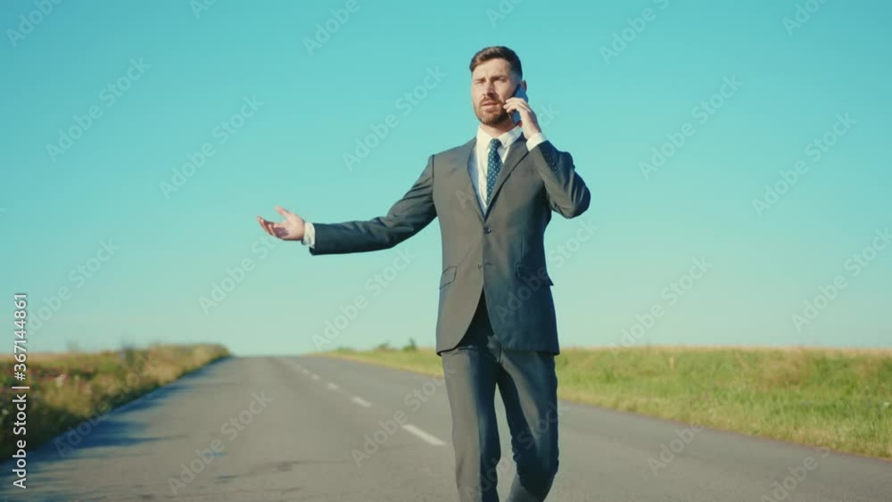 Nervous businessman talking on a smartphone walking country road near a wheat field freedom concept outdoors handsome elegant slow motion Nervous businessman talking on a smartphone walking country road near a wheat field freedom concept outdoors handsome elegant slow motion