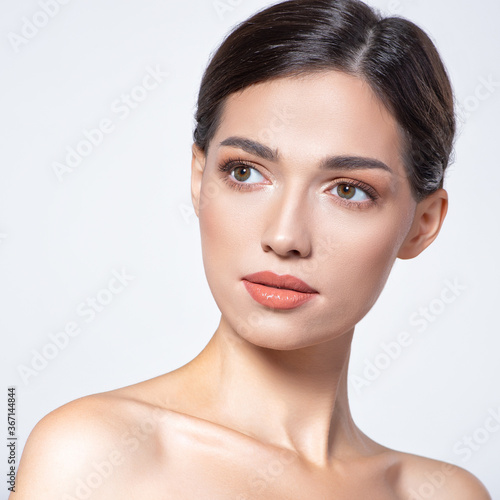 Beautiful face of young adult woman with clean fresh skin - isolated on white. Skin care. Model with perfect skin of face looking to the camera.