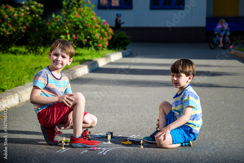 Two brothers sibling kid boy having fun with picture drawing traffic car with chalks. Creative leisure for children outdoors in summer. Difficult traffic rules education friendship concept photo