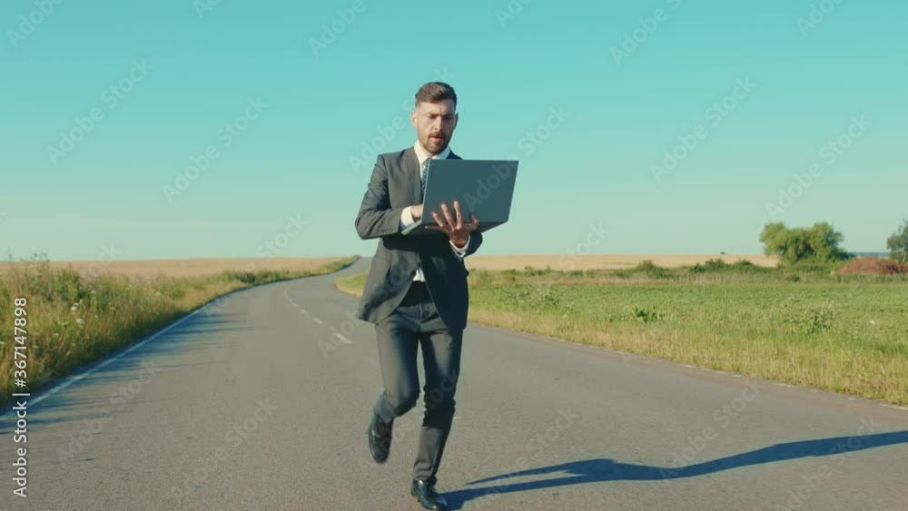 Close up businessman runs use laptop alone country road near a wheat field freedom concept outdoors handsome winner computer elegant slow motion