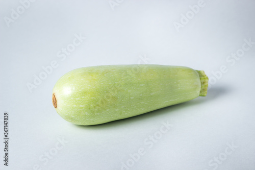 Zucchini on a white background. One fresh vegetable marrow is in the middle of the frame.