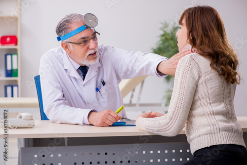 Young woman visiting old male doctor otorhinolaryngologist