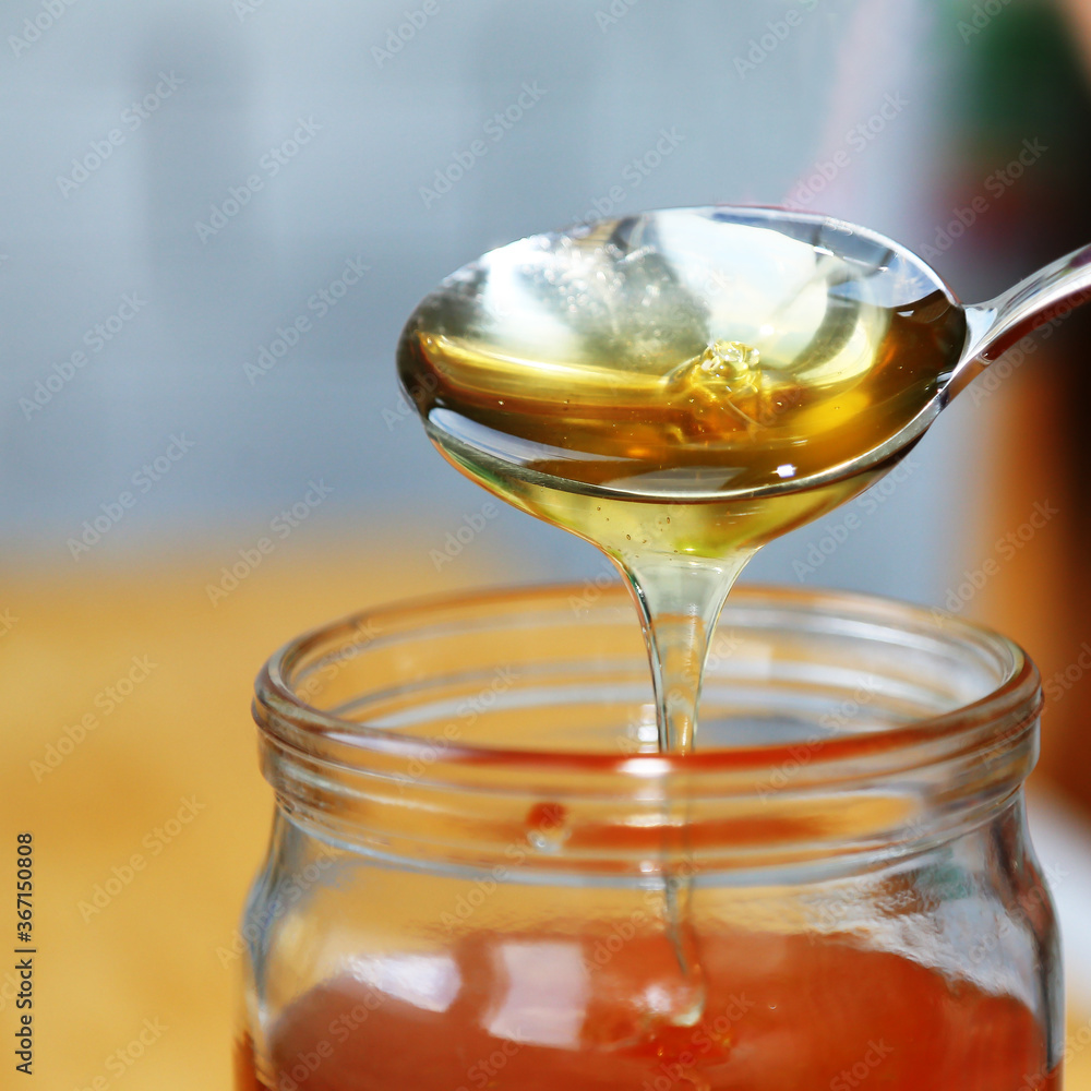 Thick honey drips from the spoon. Thick honey drips from the spoon.