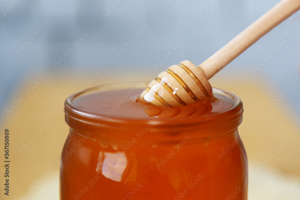 The draining spoon for honey is in a jar with bee honey. Wooden spoon for med. A glass jar filled to the top with honey. Close-up view. Cooking. Sweet food. Natural food. Healthy diet. The draining spoon for honey is in a jar with bee honey. Wooden spoon for med. A glass jar filled to the top with honey. Close-up view. Cooking. Sweet food. Natural food. Healthy diet.