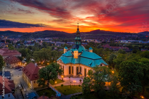 Church of the Exaltation of the Holy Cross in Jelenia Gora in Poland and the surrounding mountains with at beautiful sunset. View of the city skyline from the drone