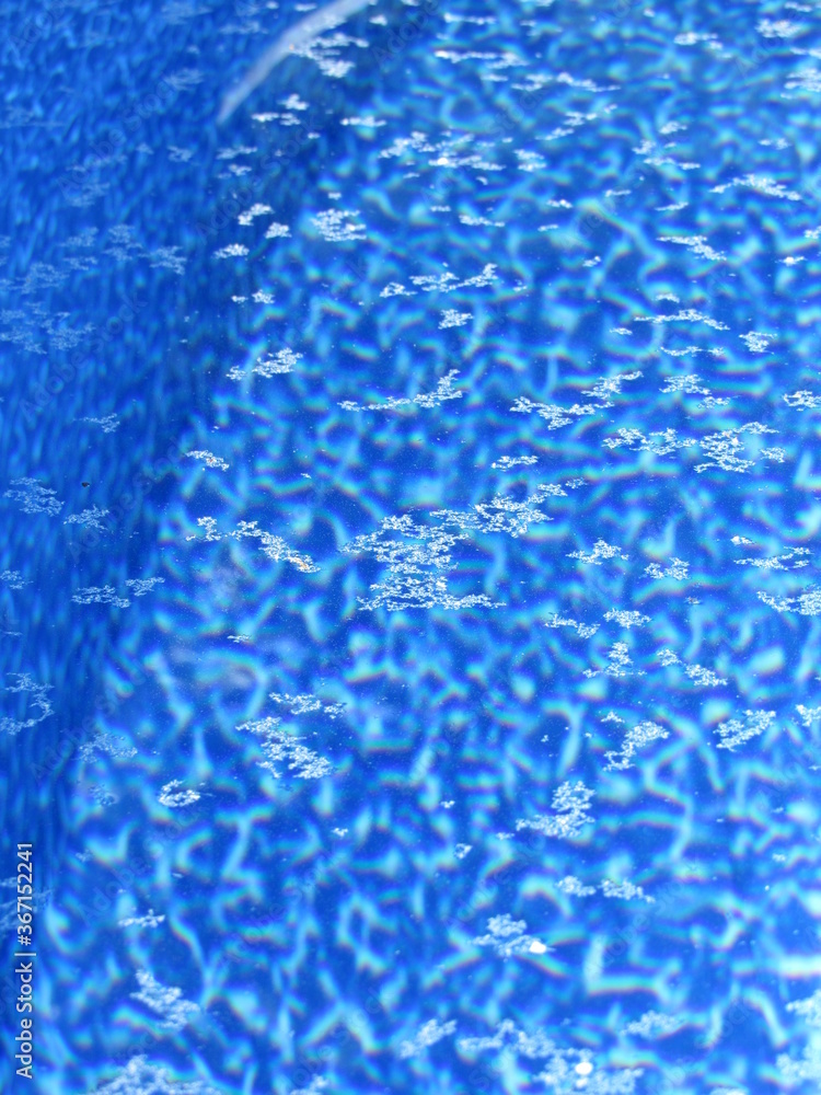 Pollen and debris on the surface of water in a pool with a blue