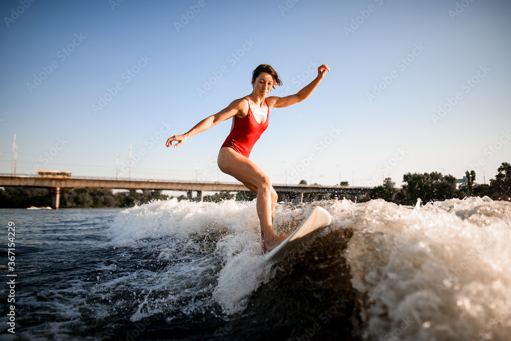 active woman masterfully rides the wave on surfboard