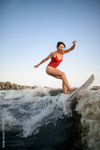 handsome woman masterfully rides the wave on surfboard