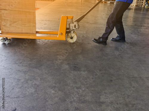 Worker driving forklift loading and unloading shipment carton boxes and goods on wooden pallet from container truck to warehouse cargo storage in logistics and transportation industrial 