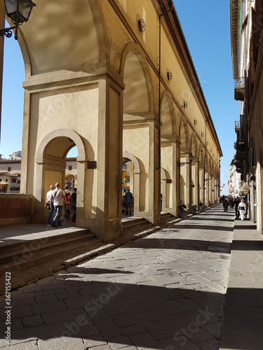 Tourists walking down the Lungarno degli Archibusieri avenue on a bright afternoon leading to Ponte Vechhio, Florence, Tuscany, Italy 2016 photo