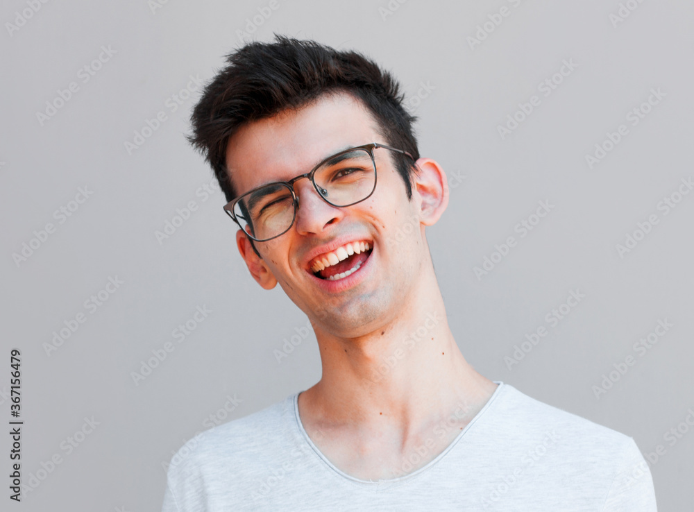 Close up portrait of young smiling handsome guy in grey t-shirt isolated on grey background Close up portrait of young smiling handsome guy in grey t-shirt isolated on grey background