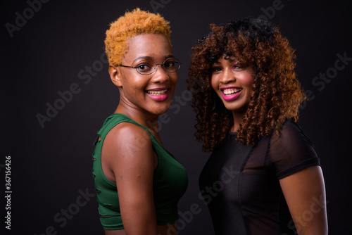 Two young African women together against black background