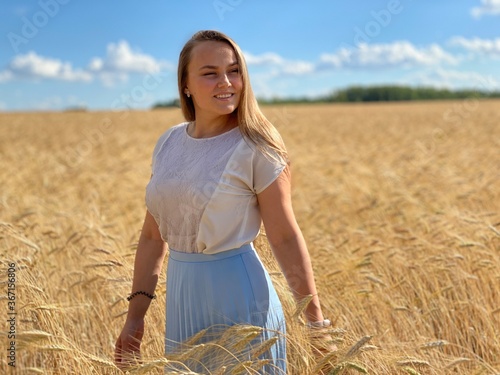 beautiful woman walks in a field with ears, takes pictures in a wheat field
