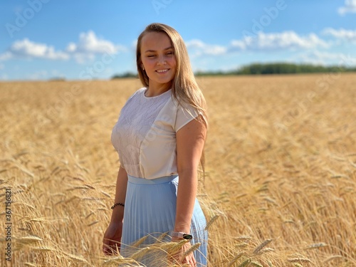 beautiful woman walks in a field with ears, takes pictures in a wheat field
