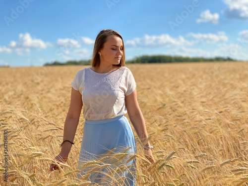 beautiful woman walks in a field with ears, takes pictures in a wheat field
