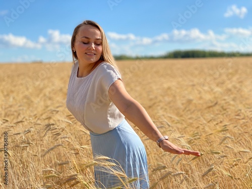 beautiful woman walks in a field with ears, takes pictures in a wheat field
