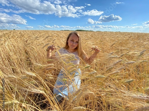 beautiful woman walks in a field with ears, takes pictures in a wheat field
