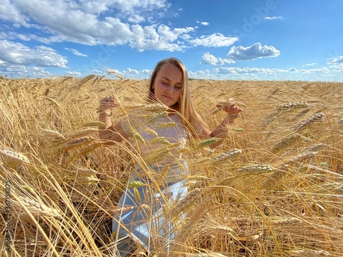 beautiful woman walks in a field with ears, takes pictures in a wheat field
