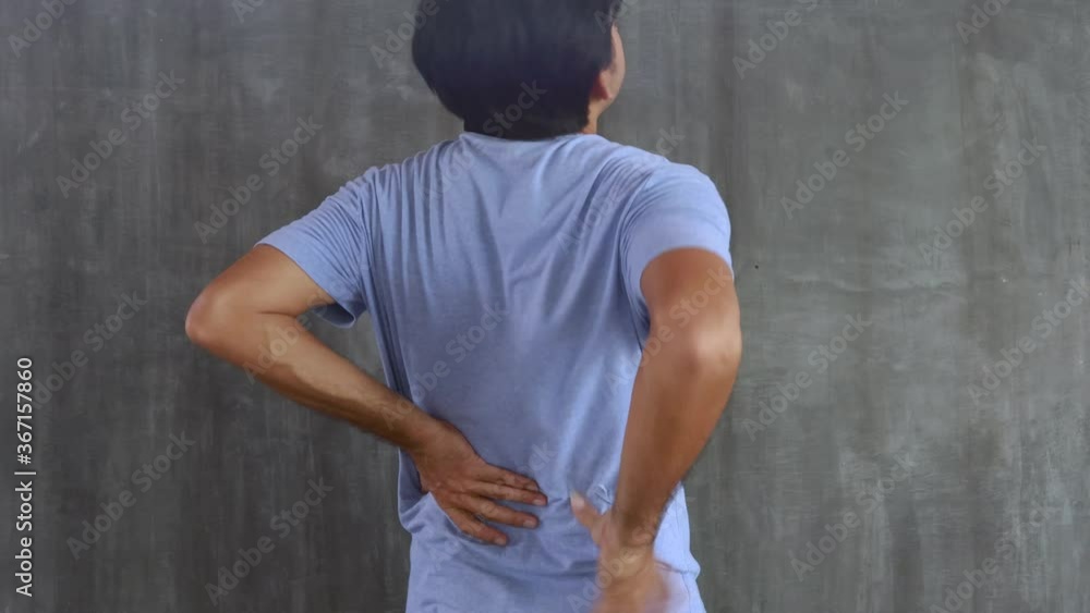 Young Asian man have back pain on concrete wall background Young Asian man have back pain on concrete wall background