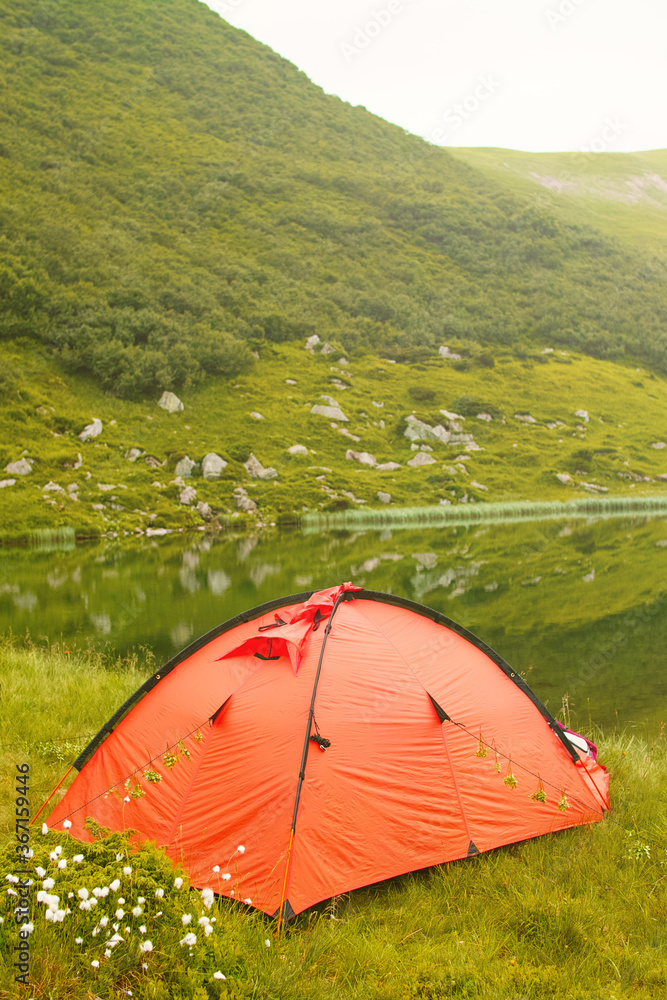 Orange tent near the lake in the mountains Orange tent near the lake in the mountains