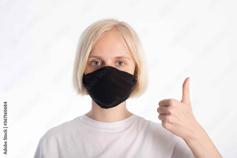 portrait of a young girl with light hair and blue eyes in a black mask (virus deterrent). the girl shows the like sign with her left hand portrait of a young girl with light hair and blue eyes in a black mask (virus deterrent). the girl shows the like sign with her left hand