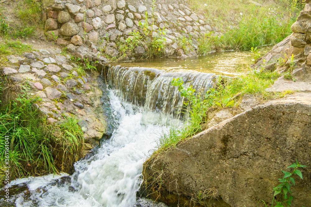 Beautiful sunny waterfall of a mountain river. Old stone bridge with seething water Beautiful sunny waterfall of a mountain river. Old stone bridge with seething water