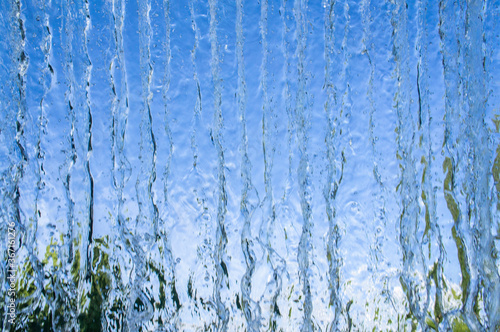 The texture of a transparent water wall from jets of water flows down. Close-up view