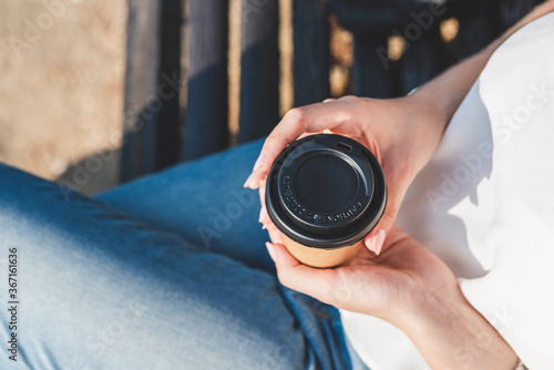 cup of take away coffee in the hands of a caucasian woman dressing casual photo