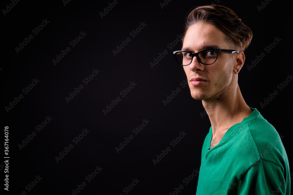 Young handsome rebellious man against black background
