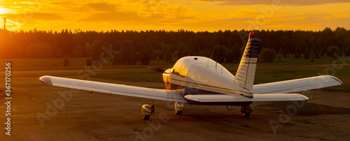 Rear view of a parked small plane on a sunset background. Silhouette of a private airplane landed at dusk.