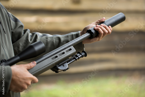 Military holds a pistol with a silencer.