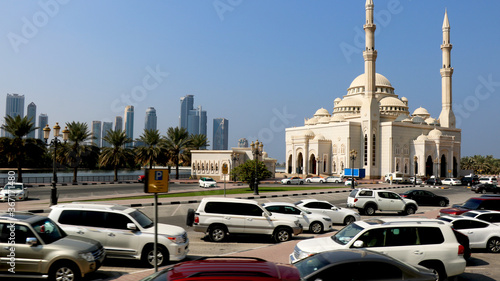 Car's park in open parking lot in Dubai with background of building and mosque