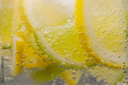 Lemon and lime slices in water with bubbles. Blurred background.