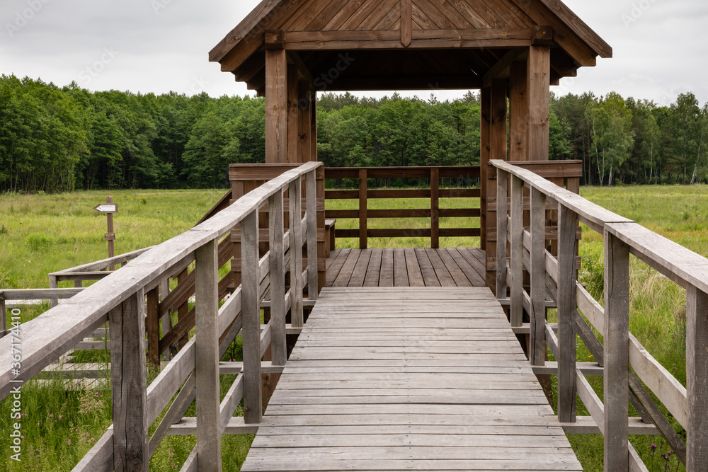 Ramp slip-way entrance to wooden gate of tower for tourist. Marshland bog in Poleski National Park. Observing tower in grassland. Nature trail Czahary. Ramp slip-way entrance to wooden gate of tower for tourist. Marshland bog in Poleski National Park. Observing tower in grassland. Nature trail Czahary.