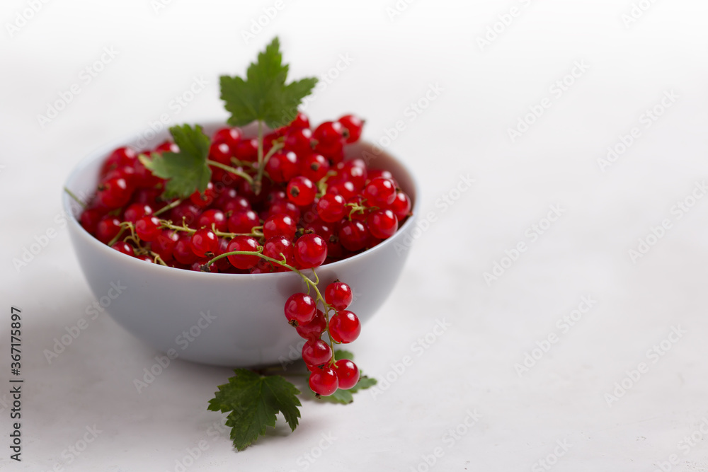 Red currants in a bowl on a light table with space for text Red currants in a bowl on a light table with space for text
