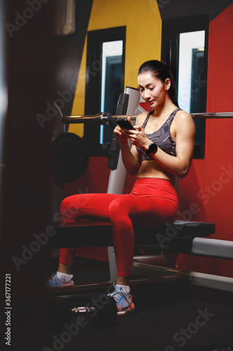 asian woman using smartphone in gym