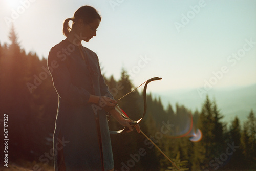 Obraz na plátně Woman shooting with a bow in the mountains